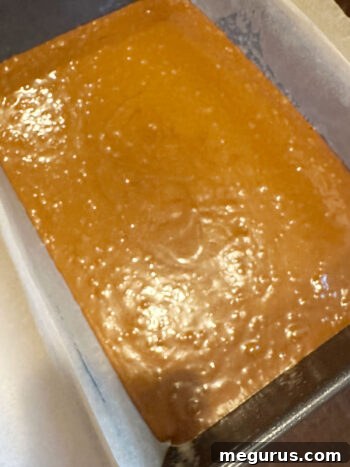 The gingerbread cake batter evenly poured into the parchment-lined baking pan, smoothed out and ready for the oven.
