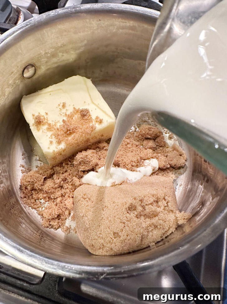Combining rich heavy cream with melted butter and both light and dark brown sugars in a saucepan to begin making caramel sauce.
