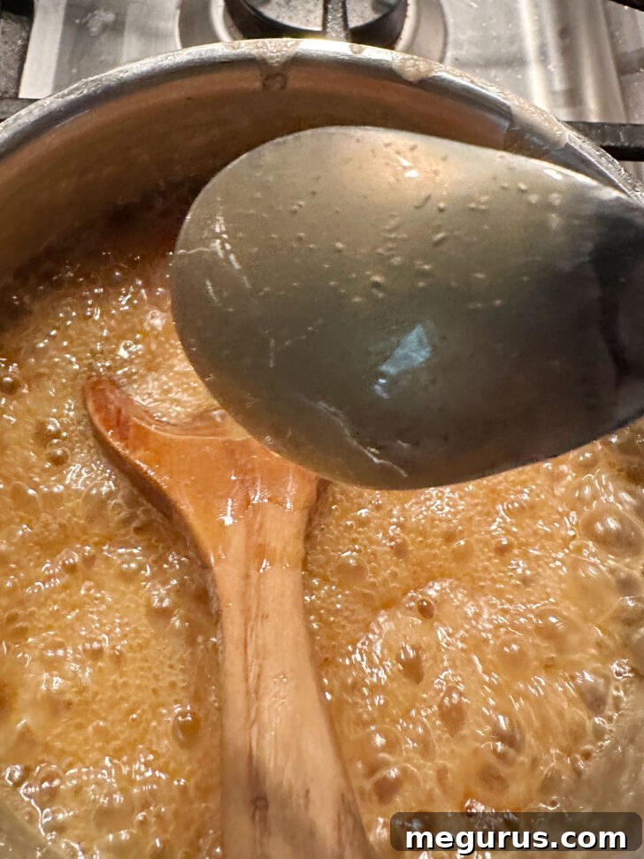 Testing the caramel sauce's consistency by observing it coating the back of a spoon, indicating it's perfectly thickened.
