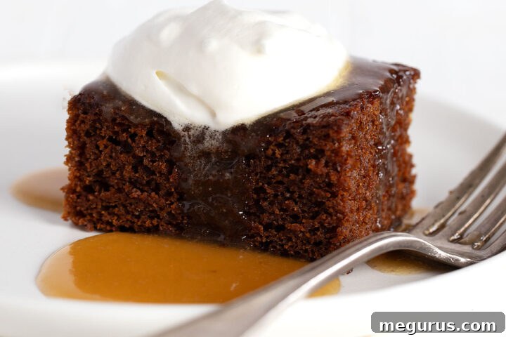Classic Gingerbread Cake topped with caramel sauce and whipped cream, presented on a white plate