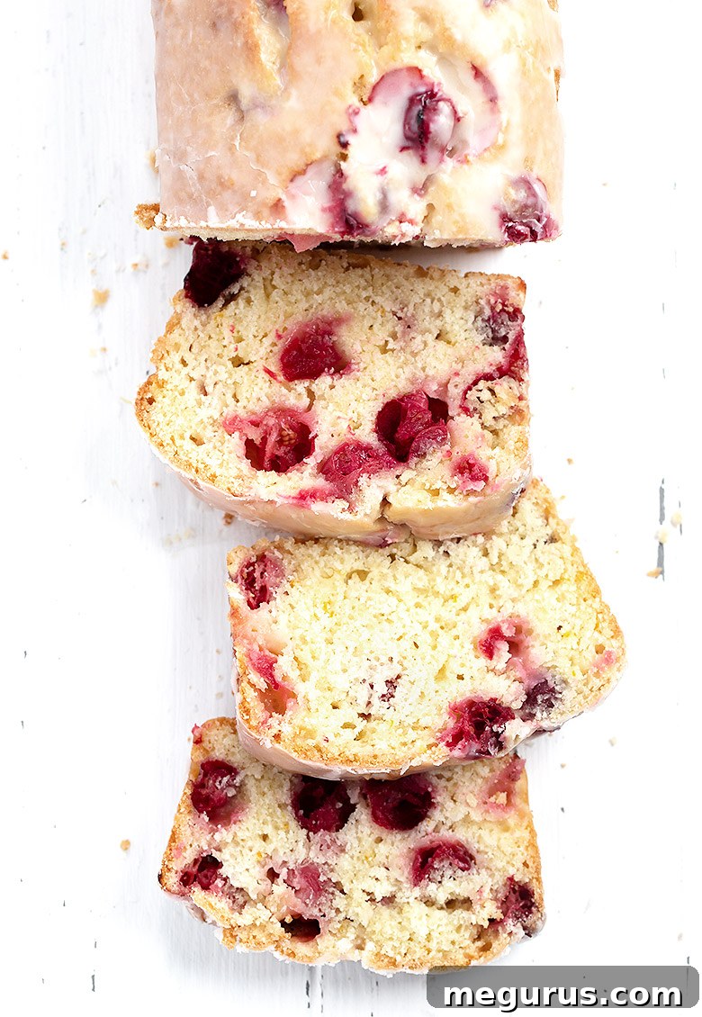 Another perspective of the sliced cranberry orange loaf on a white background