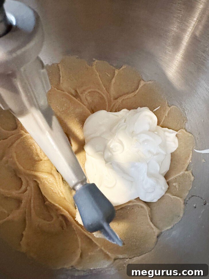 Adding the sour cream to the wet batter mixture.