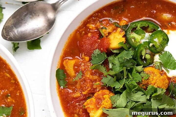 Indian spiced cauliflower soup in white bowls with spoons