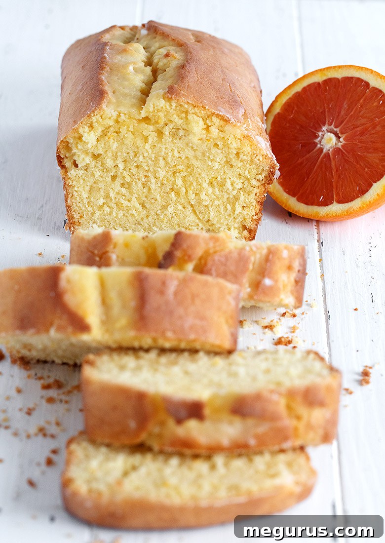 orange pound cake loaf sliced on white background with orange half