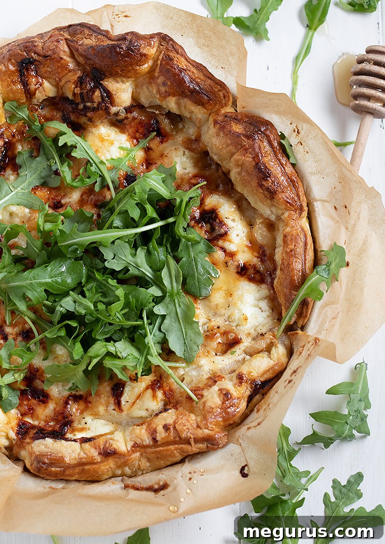 Rustic Tarte au chevre fresh out of the oven, garnished with arugula and a honey drizzle.