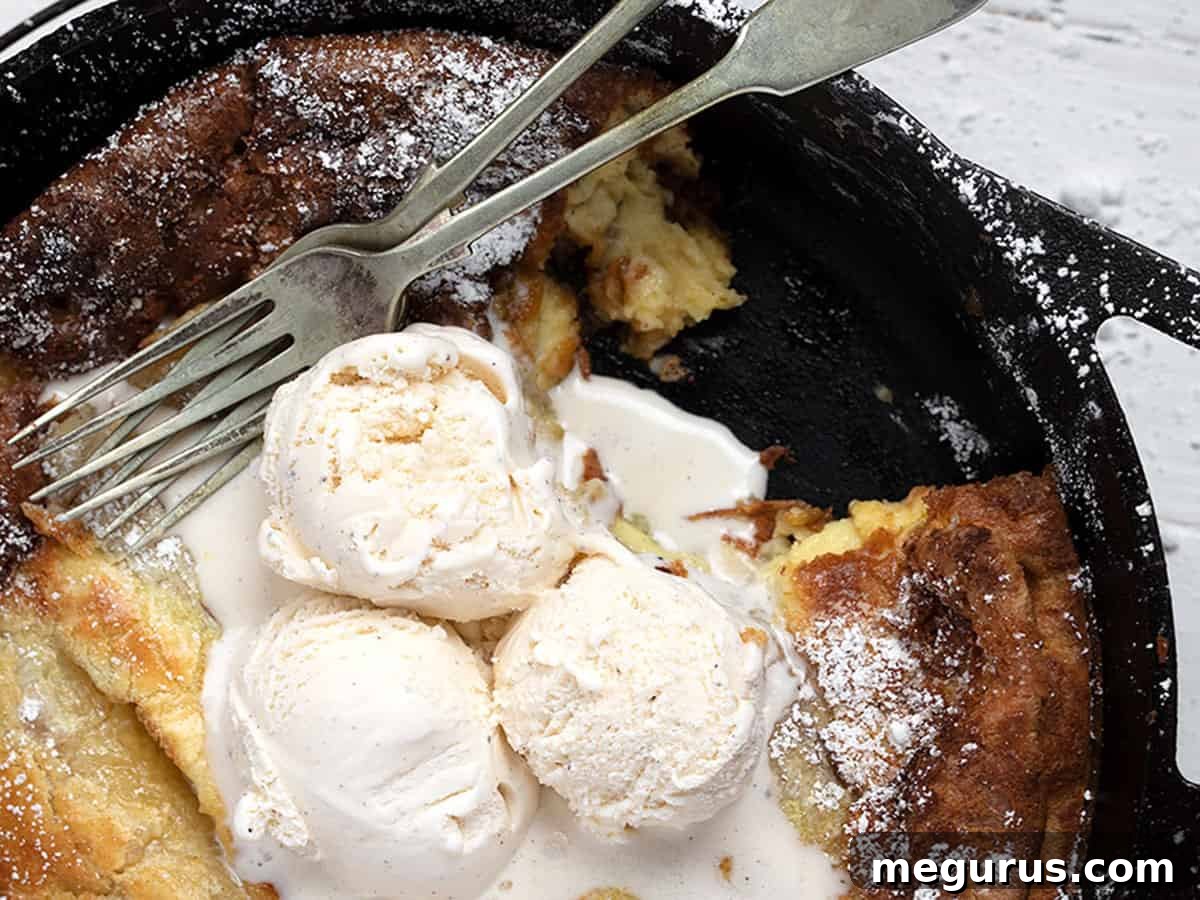 Golden-brown Bananas Foster Dutch Baby pancake in a cast iron skillet, topped with melting vanilla ice cream and glistening caramelized bananas.