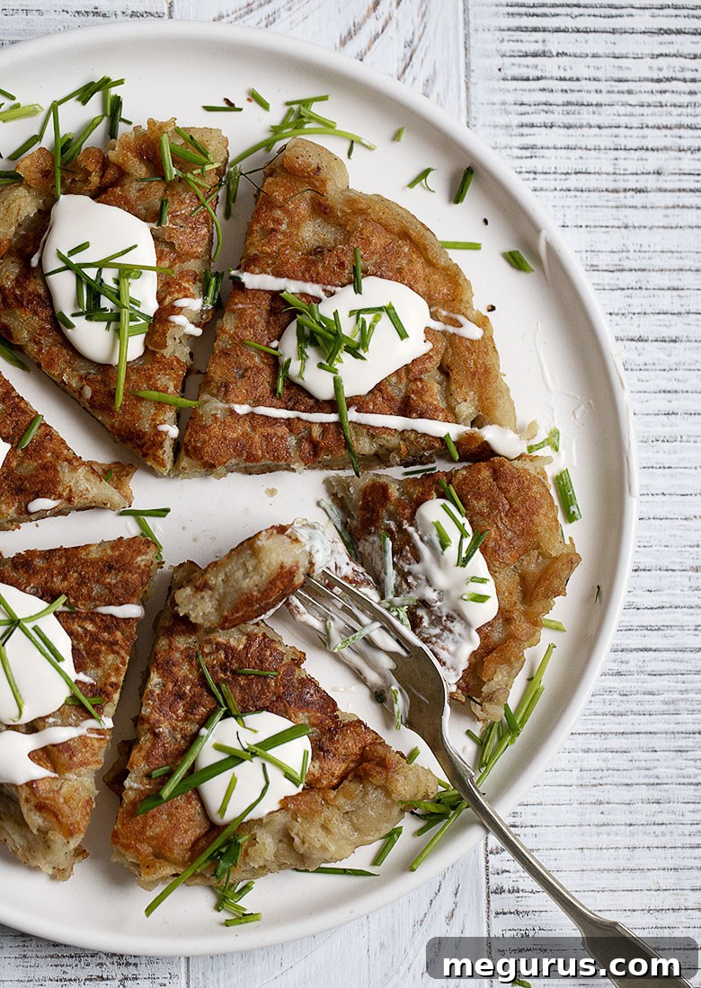 Large Irish Boxty potato cake, cooked as one round on a skillet and then cut into delicious wedges, served on a white plate.