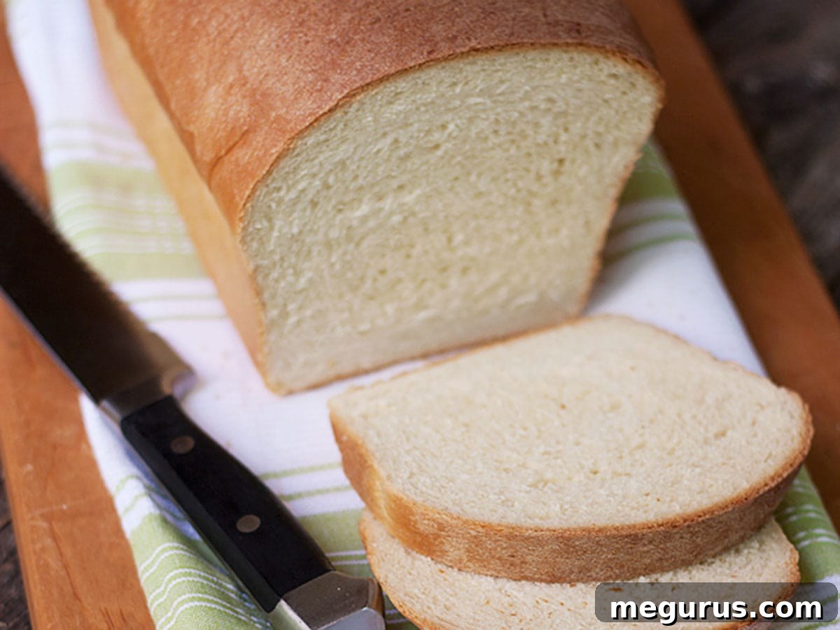 Sliced maple white sandwich bread on a wooden cutting board, showcasing its soft interior