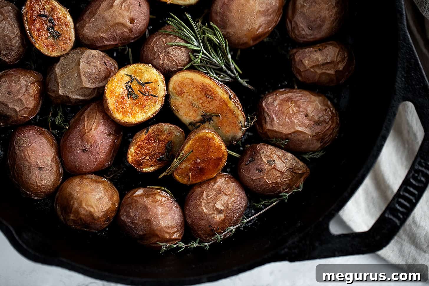 Crispy skillet baby potatoes in a cast iron skillet with fresh rosemary sprigs, ready to serve