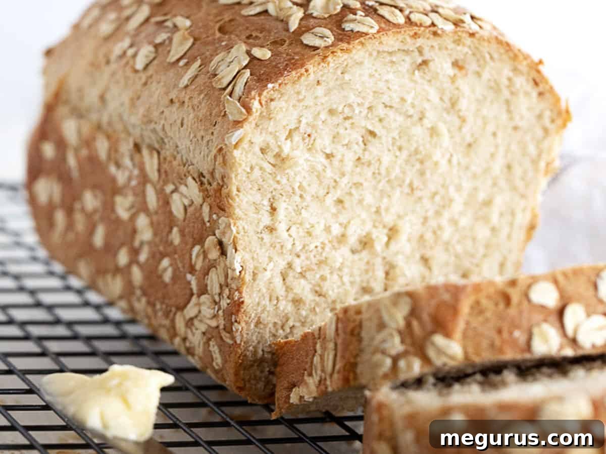 Sliced honey oatmeal bread on a cutting board, showcasing its moist texture and oat-speckled crust.