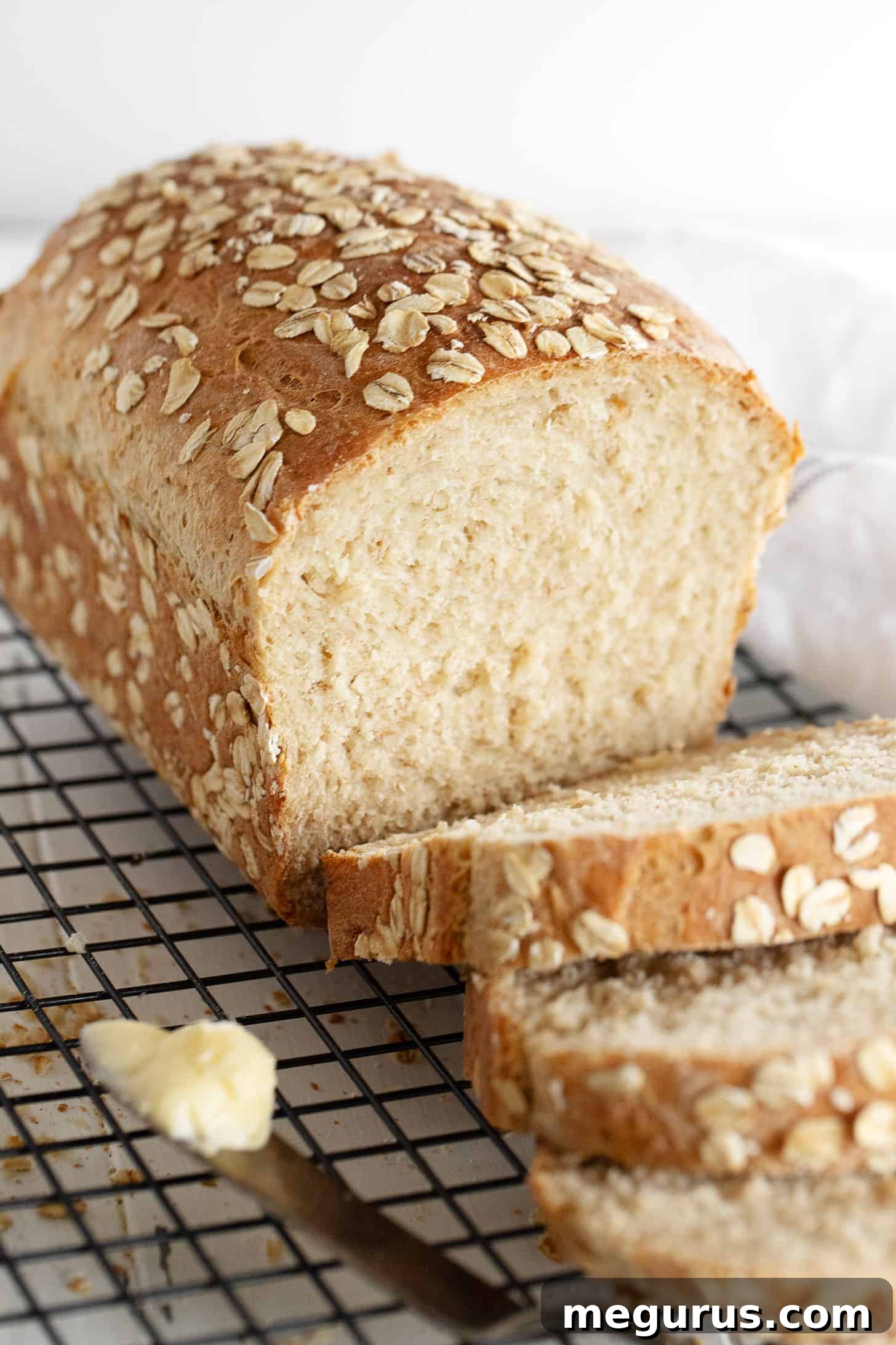Freshly baked honey oat bread, sliced and placed on a cooling rack, ready to be enjoyed.