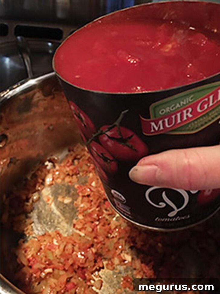 Adding the canned tomatoes to the pot,