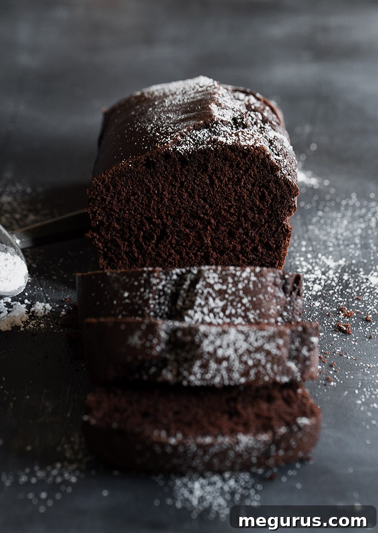Sliced chocolate pound cake loaf with a dusting of icing sugar