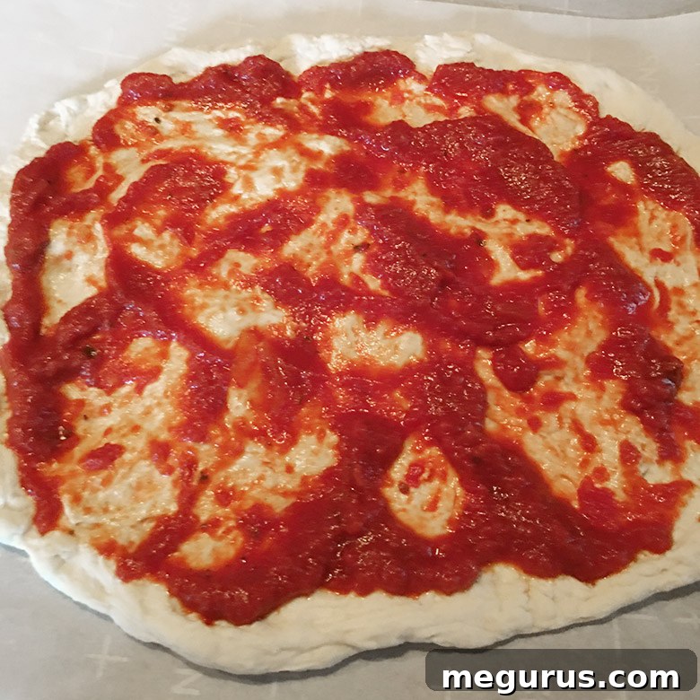 Spreading fresh, no-cook pizza sauce onto homemade pizza dough, leaving a perfect crust edge