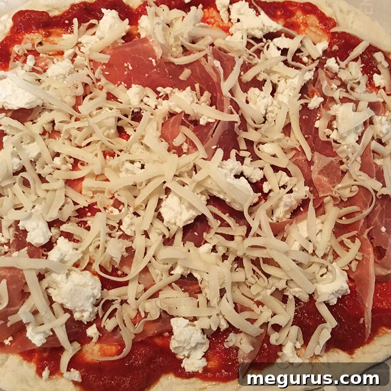 Adding a light sprinkle of mozzarella cheese over prosciutto and goat cheese on homemade pizza