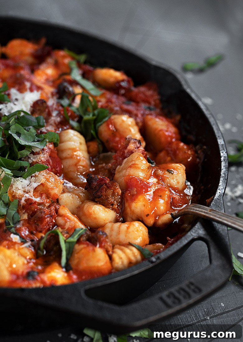 baked gnocchi with sausage in cast iron skillet with spoon