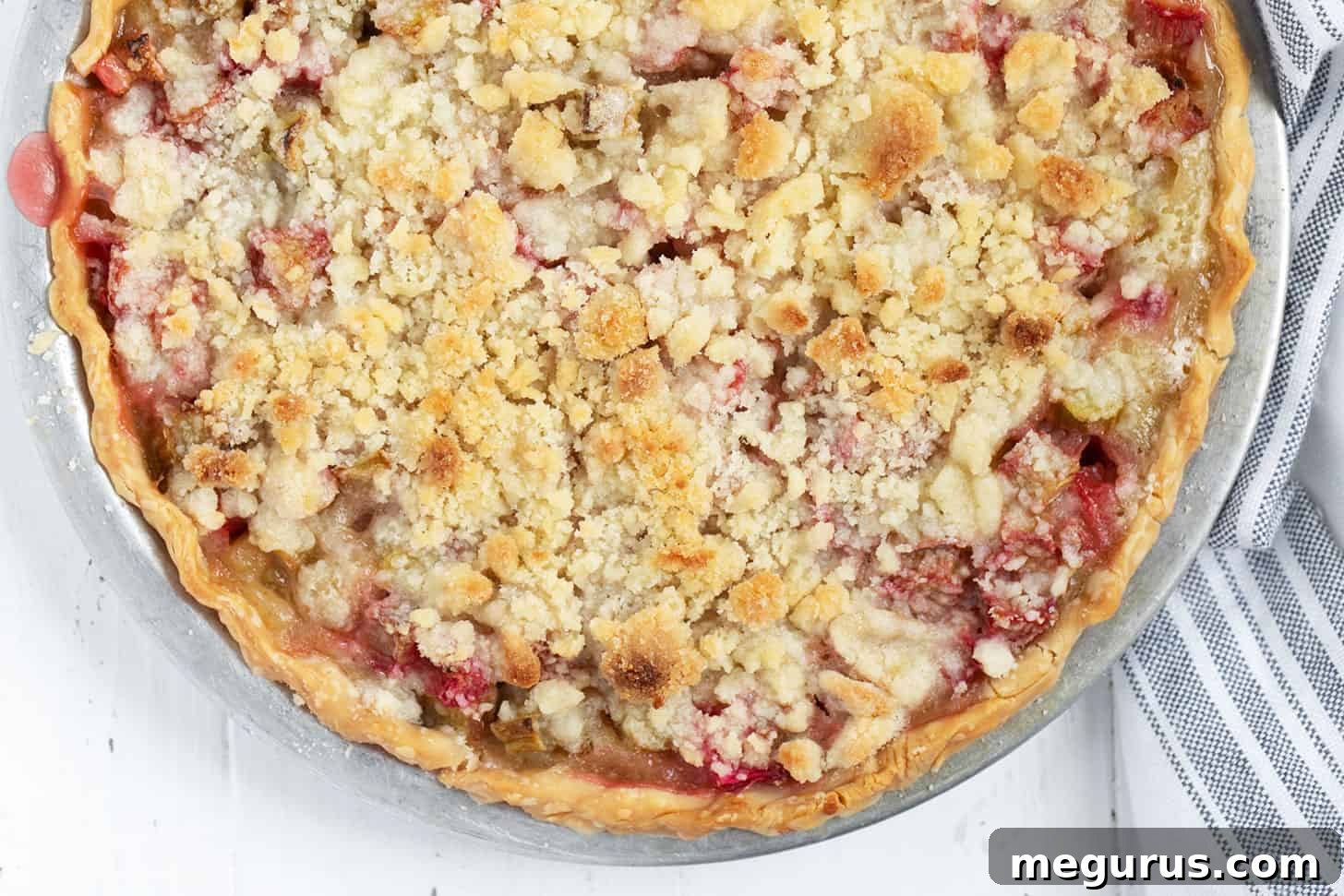 Delicious Rhubarb Crumble Pie in a ceramic pie plate, freshly baked and golden brown.