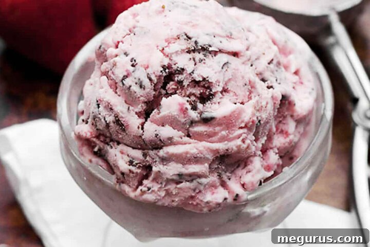 Scoop of chocolate covered strawberry ice cream in a white bowl, ready to be enjoyed.