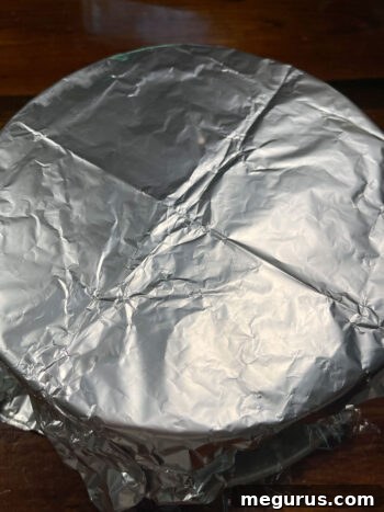 Springform pan, double-covered with plastic wrap and aluminum foil for optimal freezing.