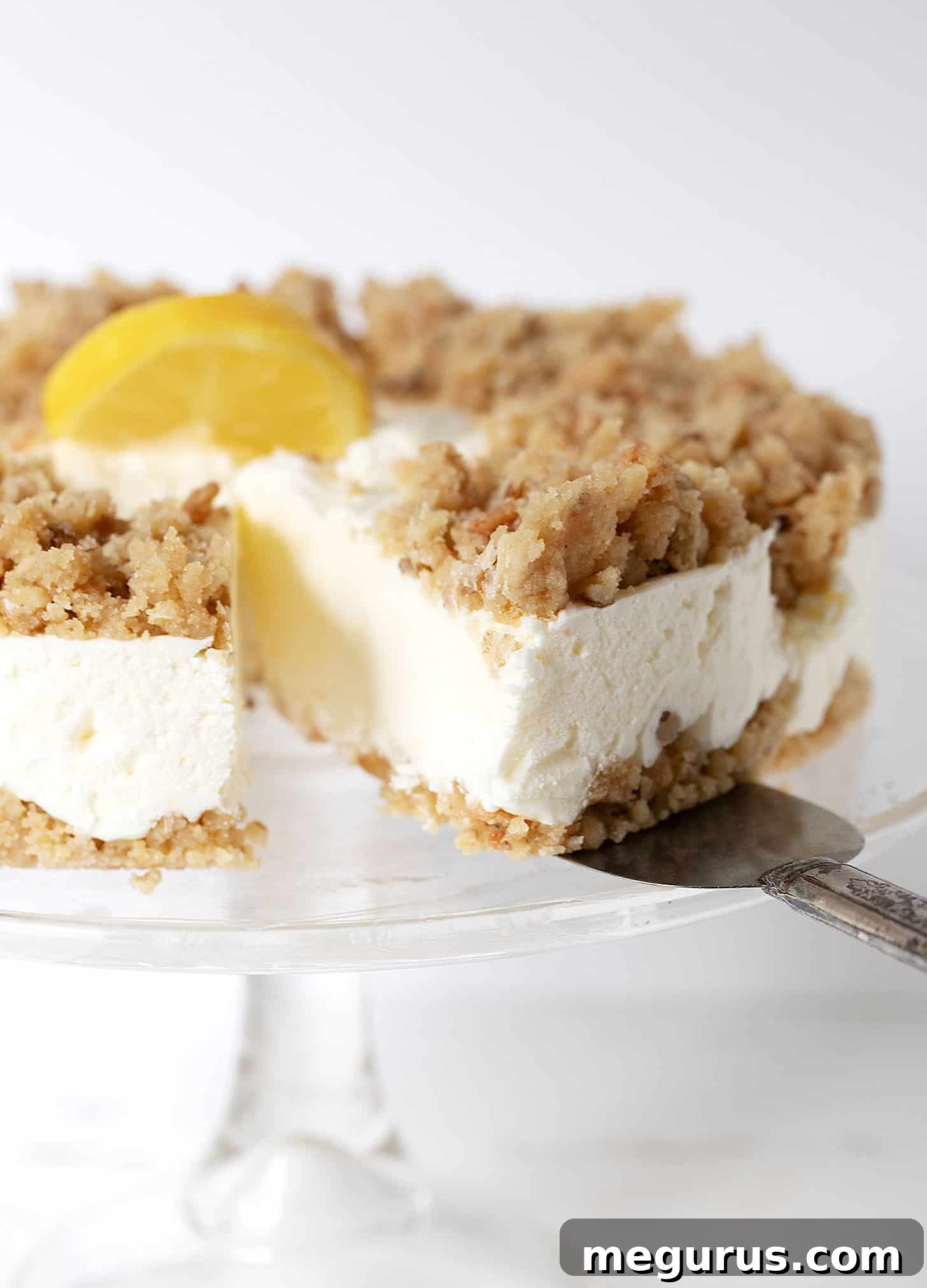 A perfectly sliced piece of frozen lemon dessert on an elegant cake plate, garnished with lemon zest.