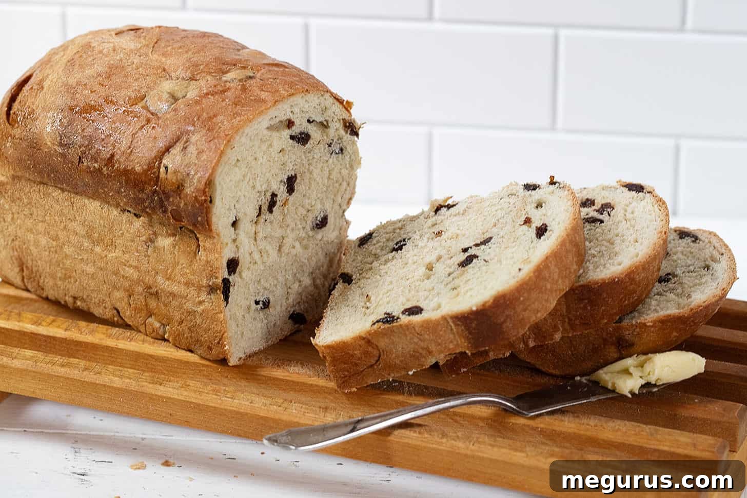 Freshly sliced classic raisin bread on a cutting rack, highlighting its soft texture and generous raisin distribution.
