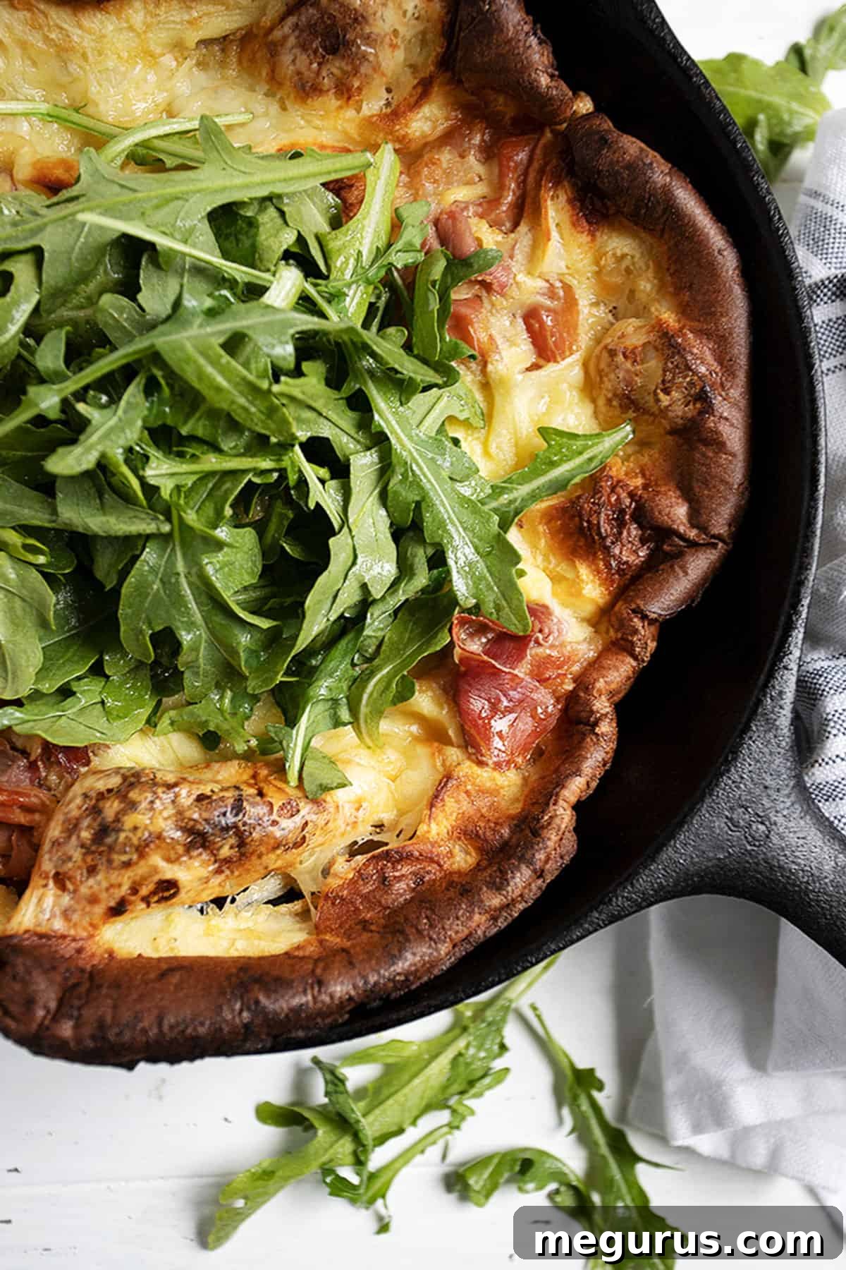 prosciutto Dutch baby in skillet with arugula