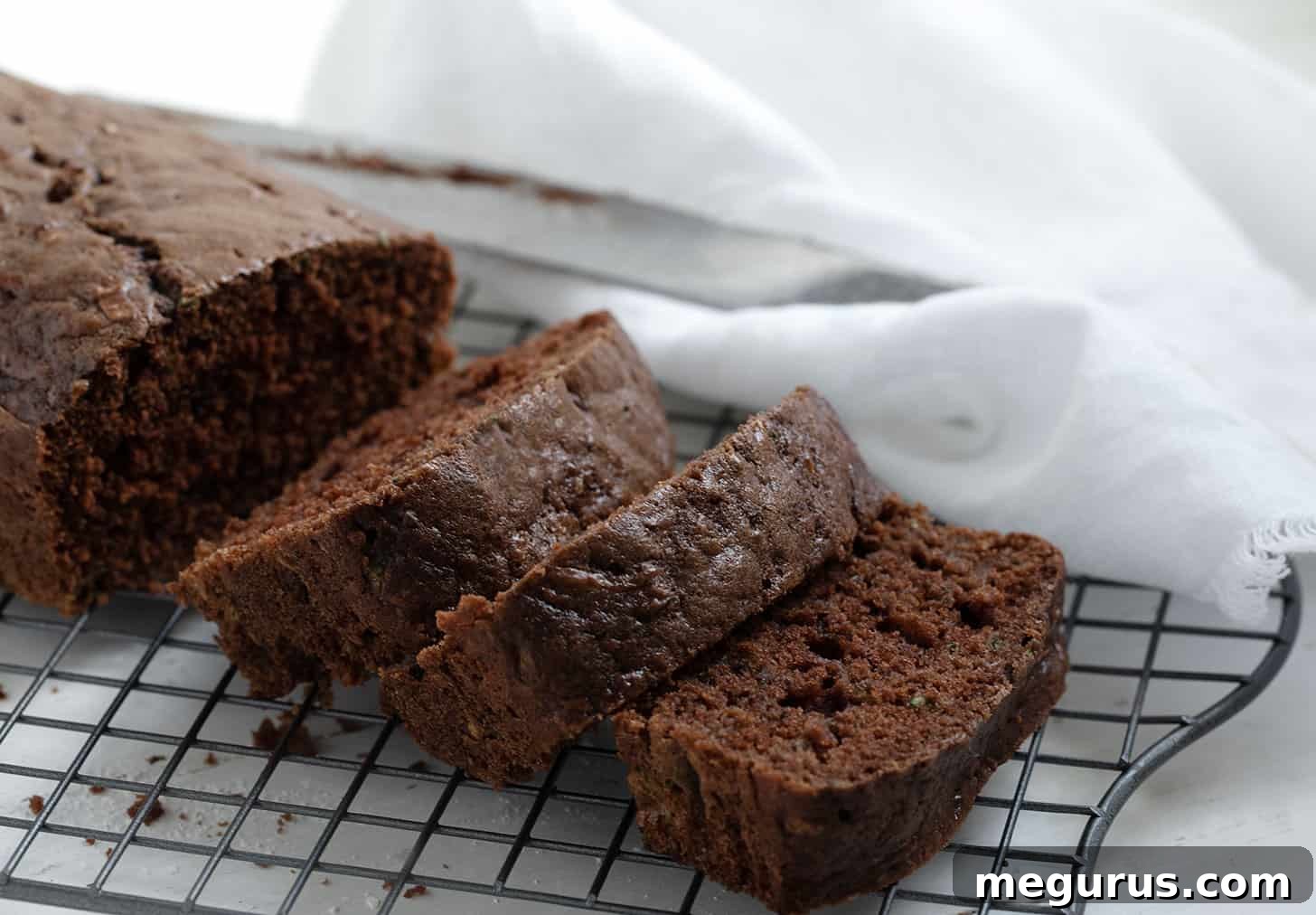 Sliced chocolate zucchini bread resting on a cooling rack, showcasing its moist texture and chocolate chips.