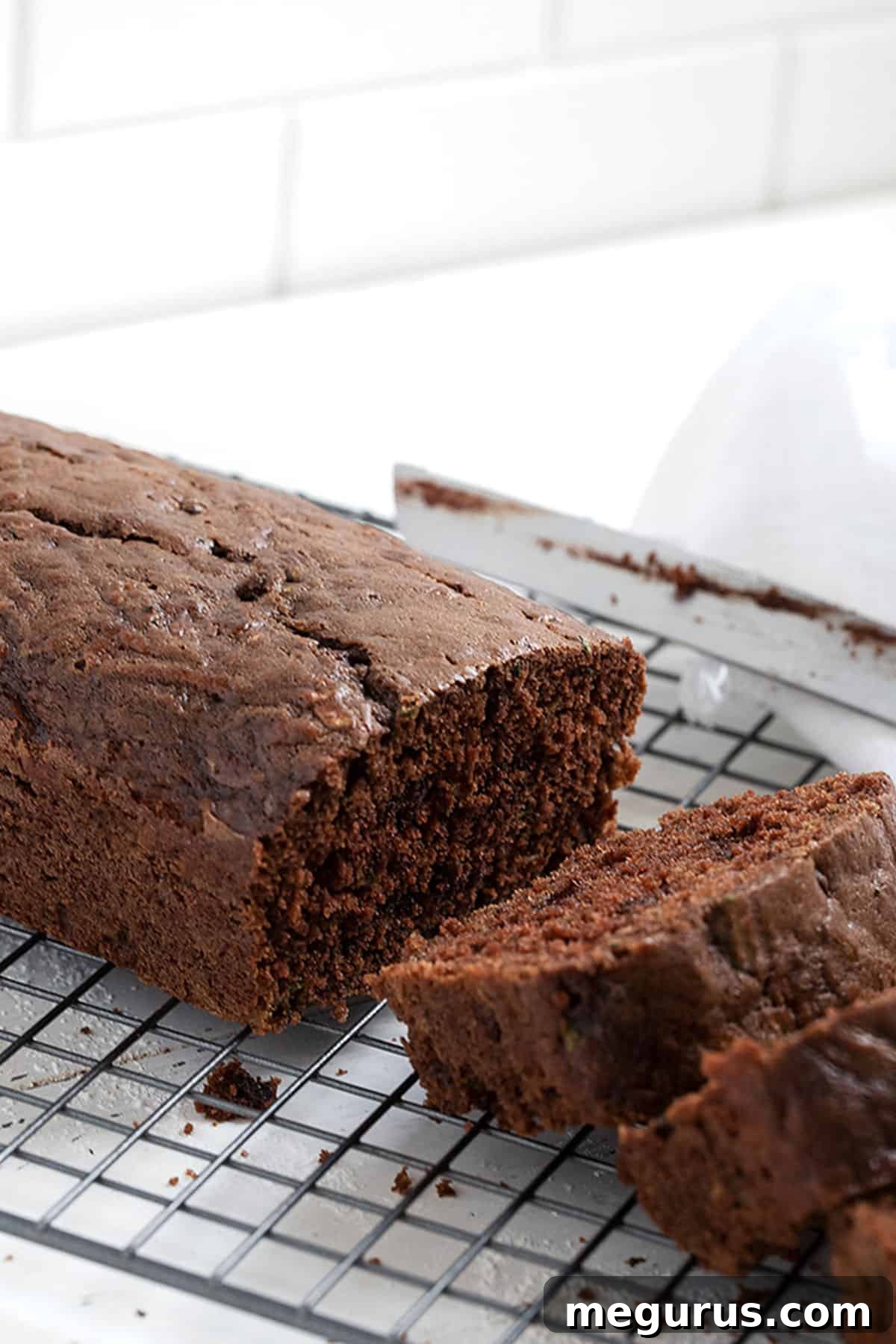 A second view of sliced chocolate zucchini bread on a cooling rack, highlighting the delicious chocolate chips and moist interior.