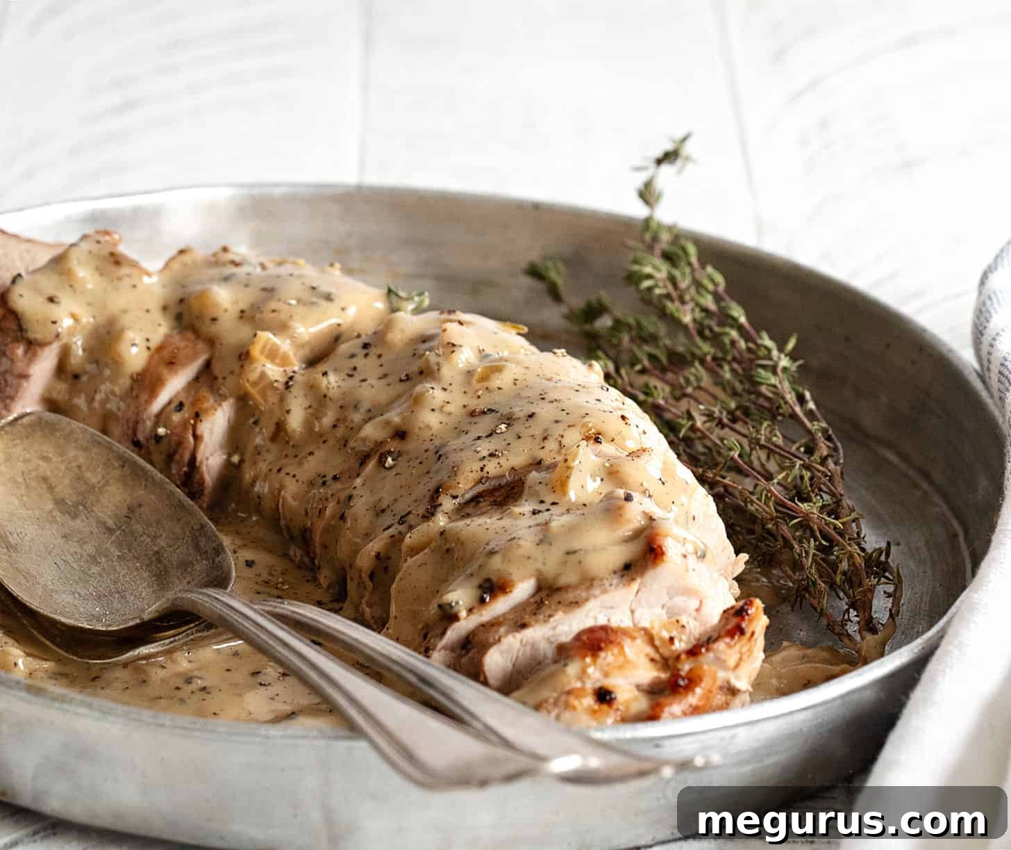 pork tenderloin sliced on platter with peppercorn gravy