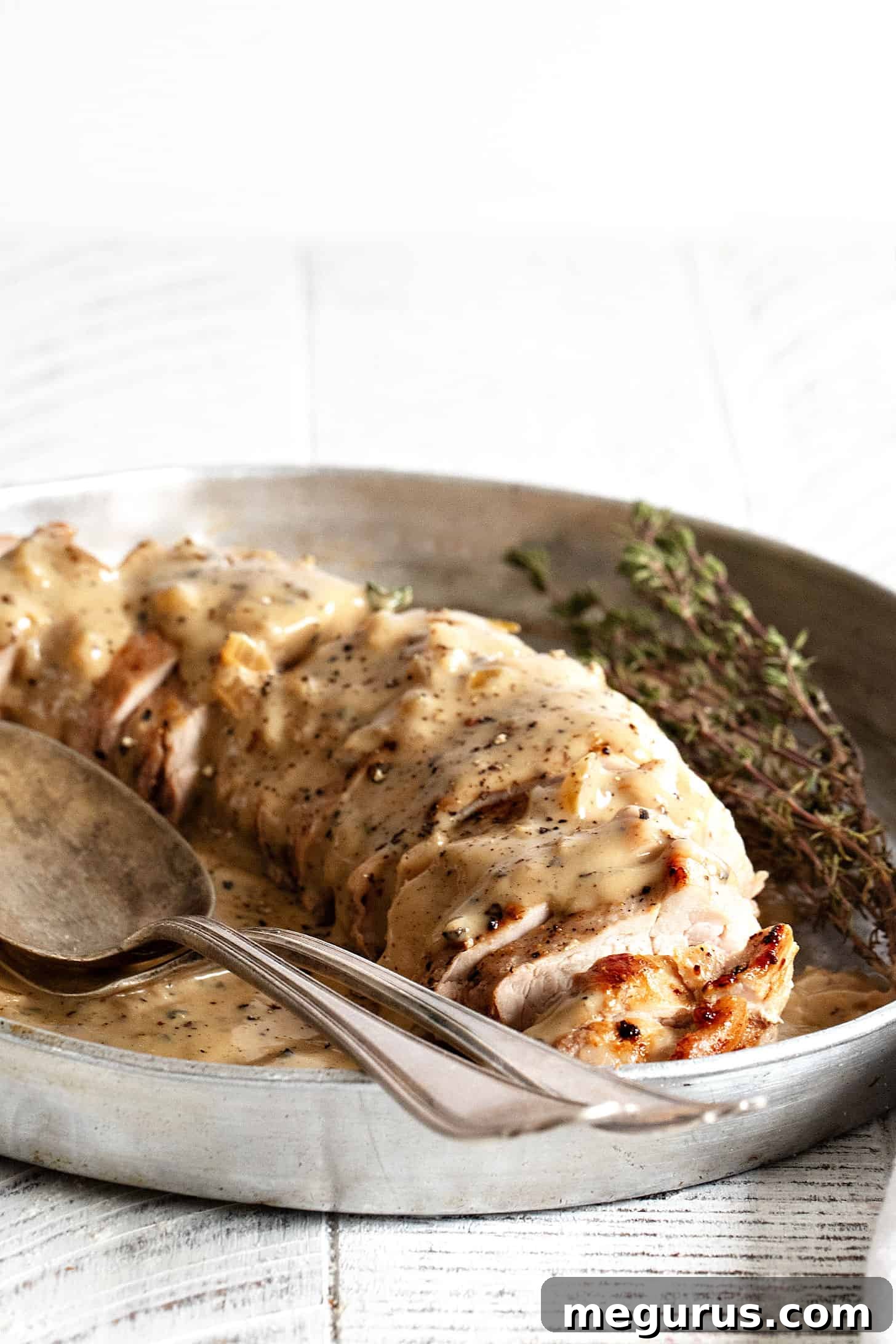 pork tenderloin sliced on platter with peppercorn gravy