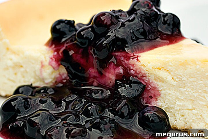 Classic cheesecake topped with homemade blueberry sauce, glistening and ready to serve.