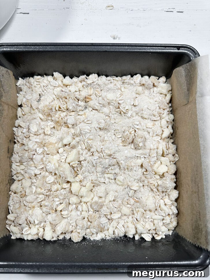 Date squares assembled in the pan, topped with crumb mixture, ready for the oven.
