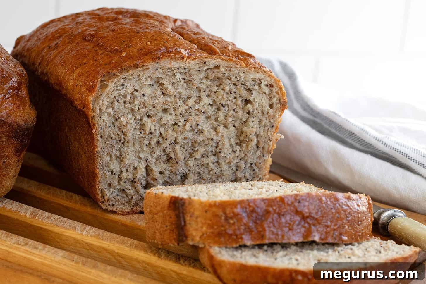 Freshly sliced whole wheat seed bread on a wooden cutting board, revealing a soft, seedy interior.