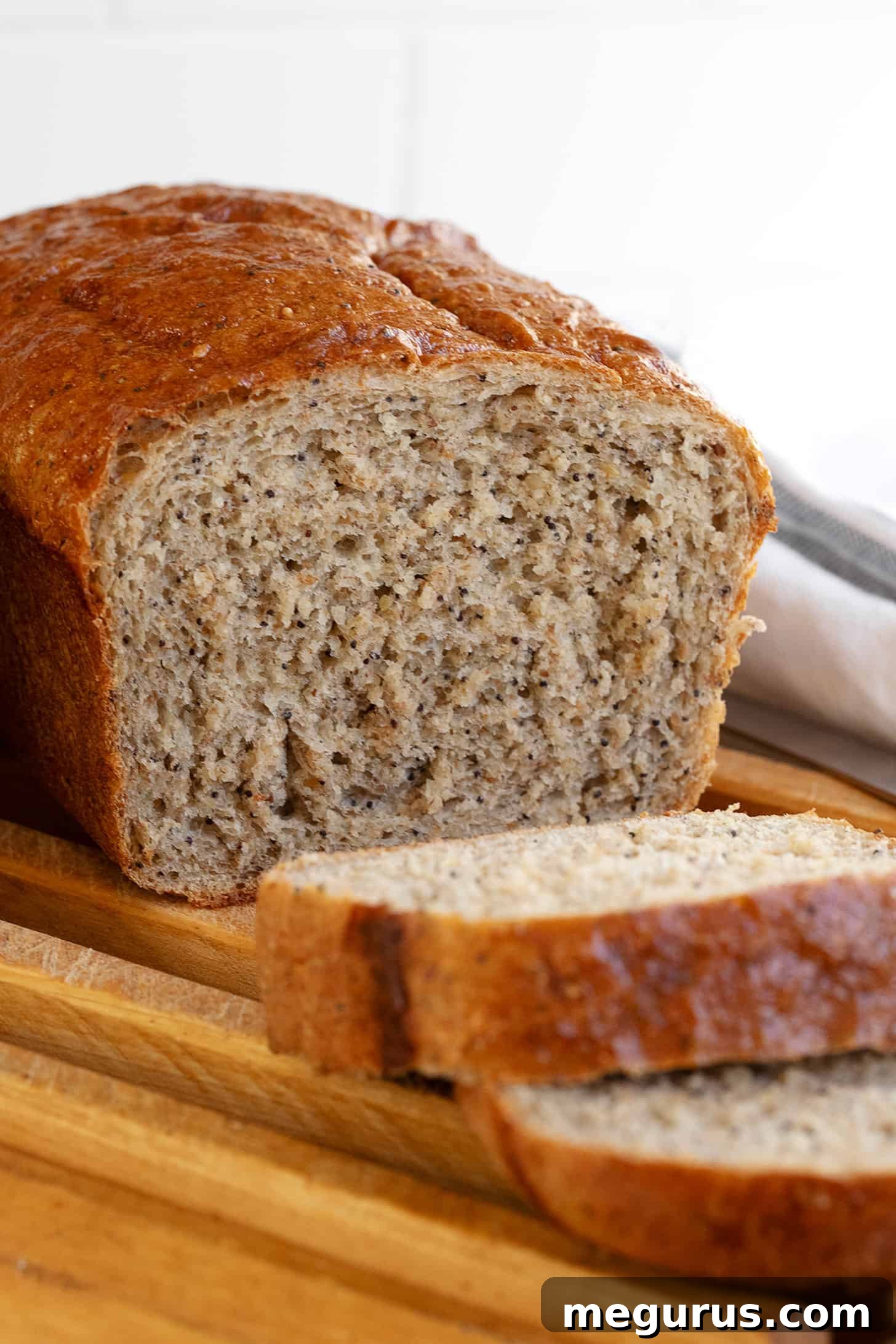 Two golden-brown loaves of whole wheat seed bread cooling on a wire rack.