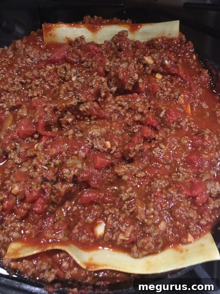Layers of sauce and fresh noodles assembled in a skillet before baking.