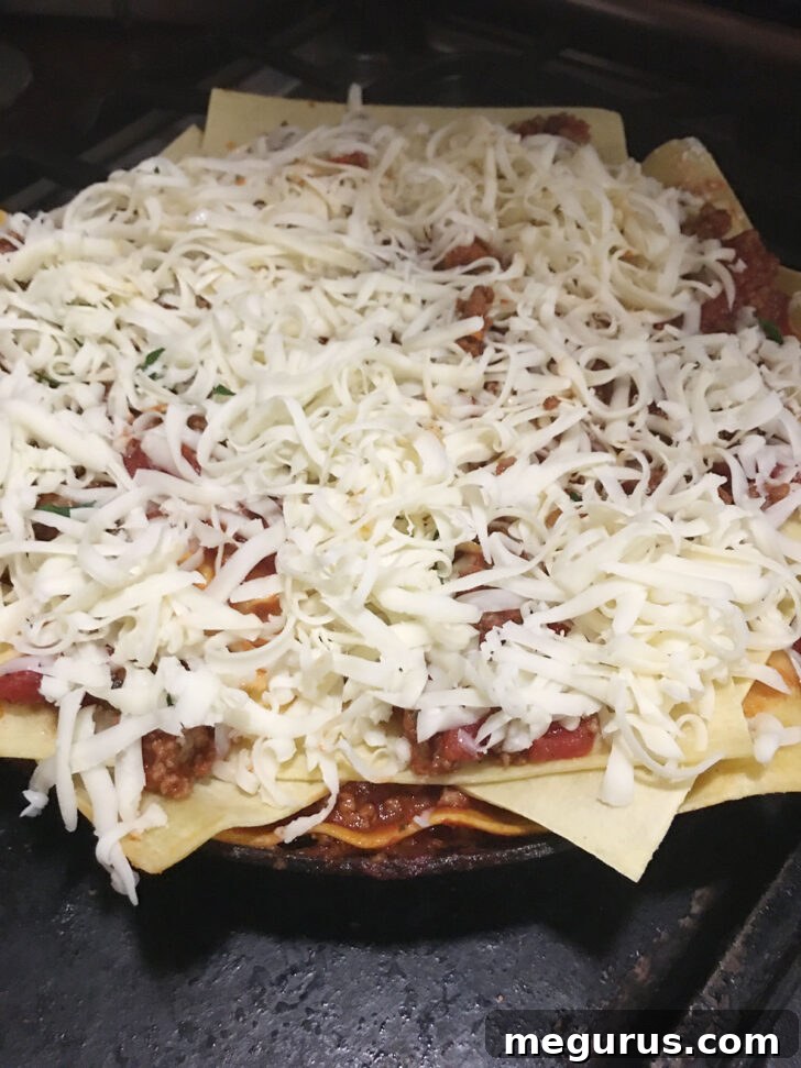 Topping the lasagna generously with shredded mozzarella cheese before baking.