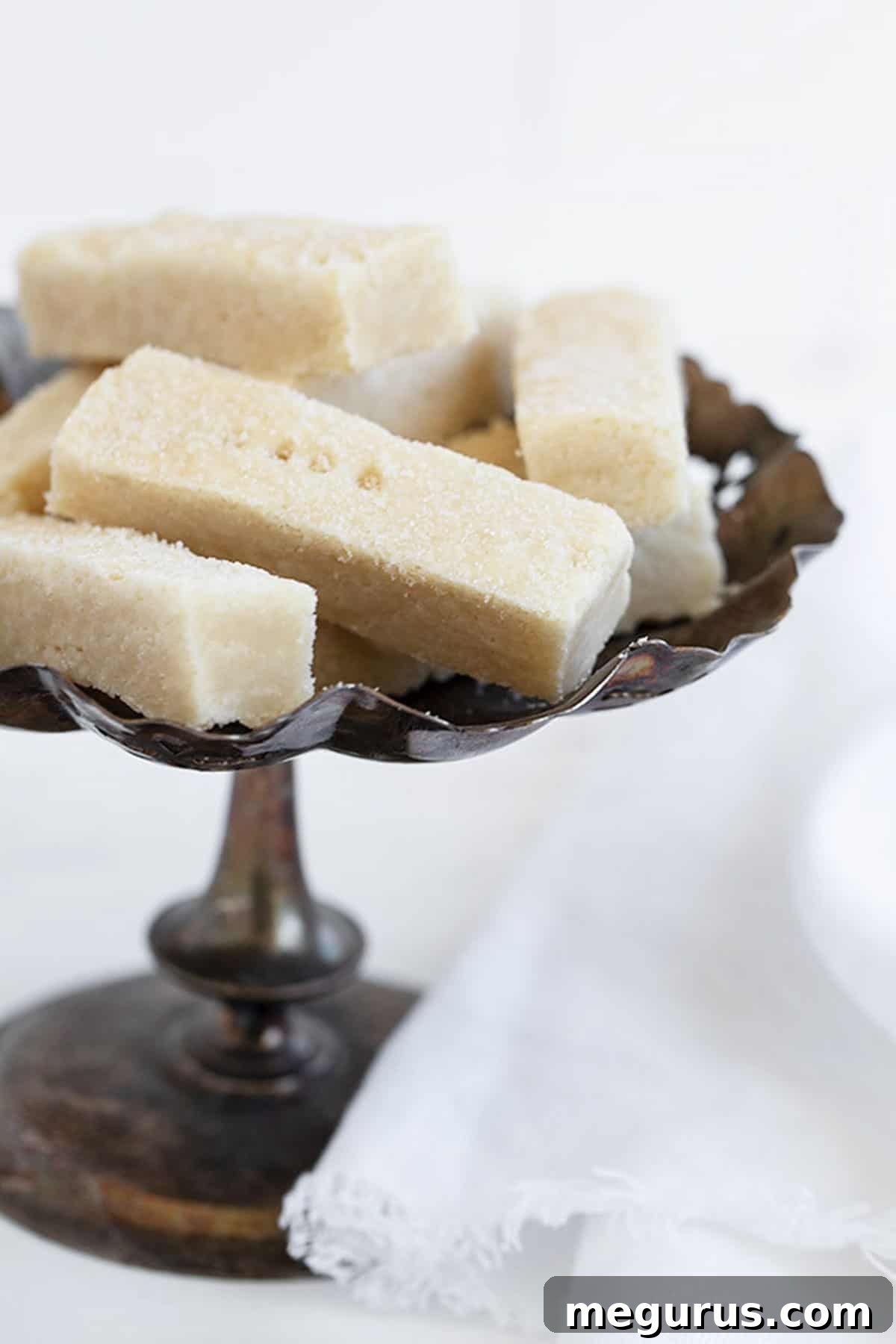Close-up of golden sheet pan shortbread cookies cooling on a vintage silver tray