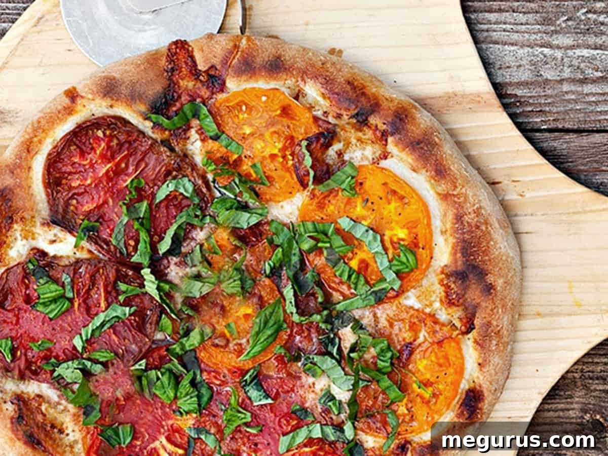 Perfectly sliced Heirloom Tomato Pizza on a wooden pizza peel, showcasing colorful tomatoes and fresh basil