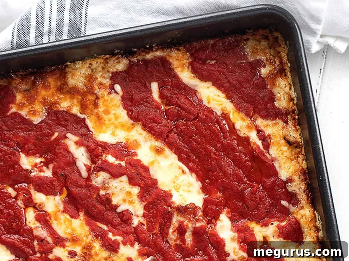 Authentic Detroit Style Pizza in a rectangular pan, fresh out of the oven, showcasing its thick crust and golden-brown edges.