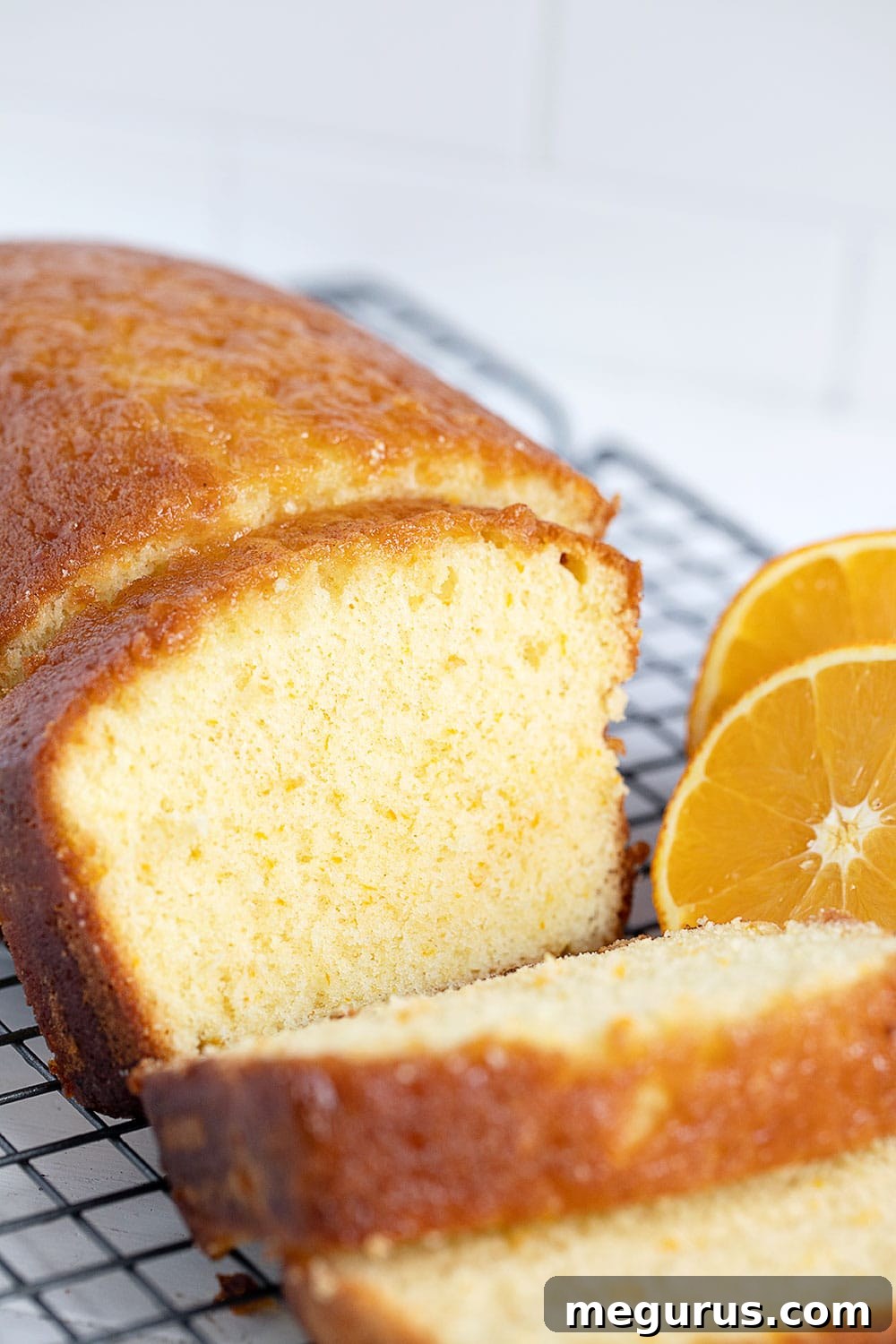 Close-up of a sliced orange drizzle loaf cake, showing its moist crumb and citrus glaze.