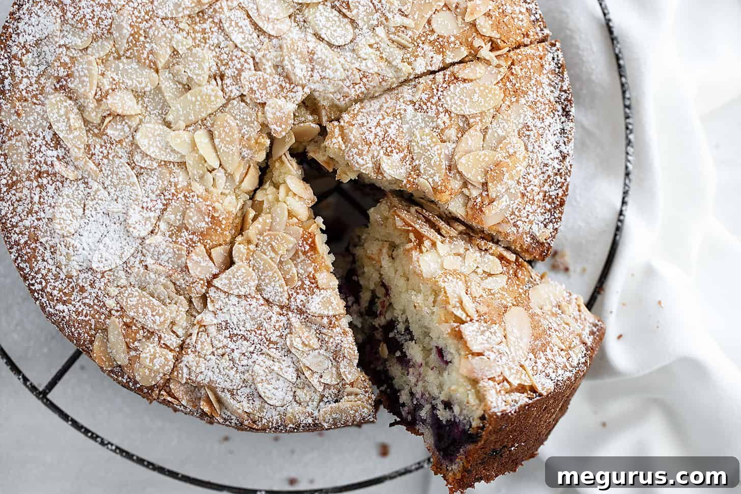 Sliced Blueberry Muffin Cake on a cooling rack, showing its moist crumb and blueberries