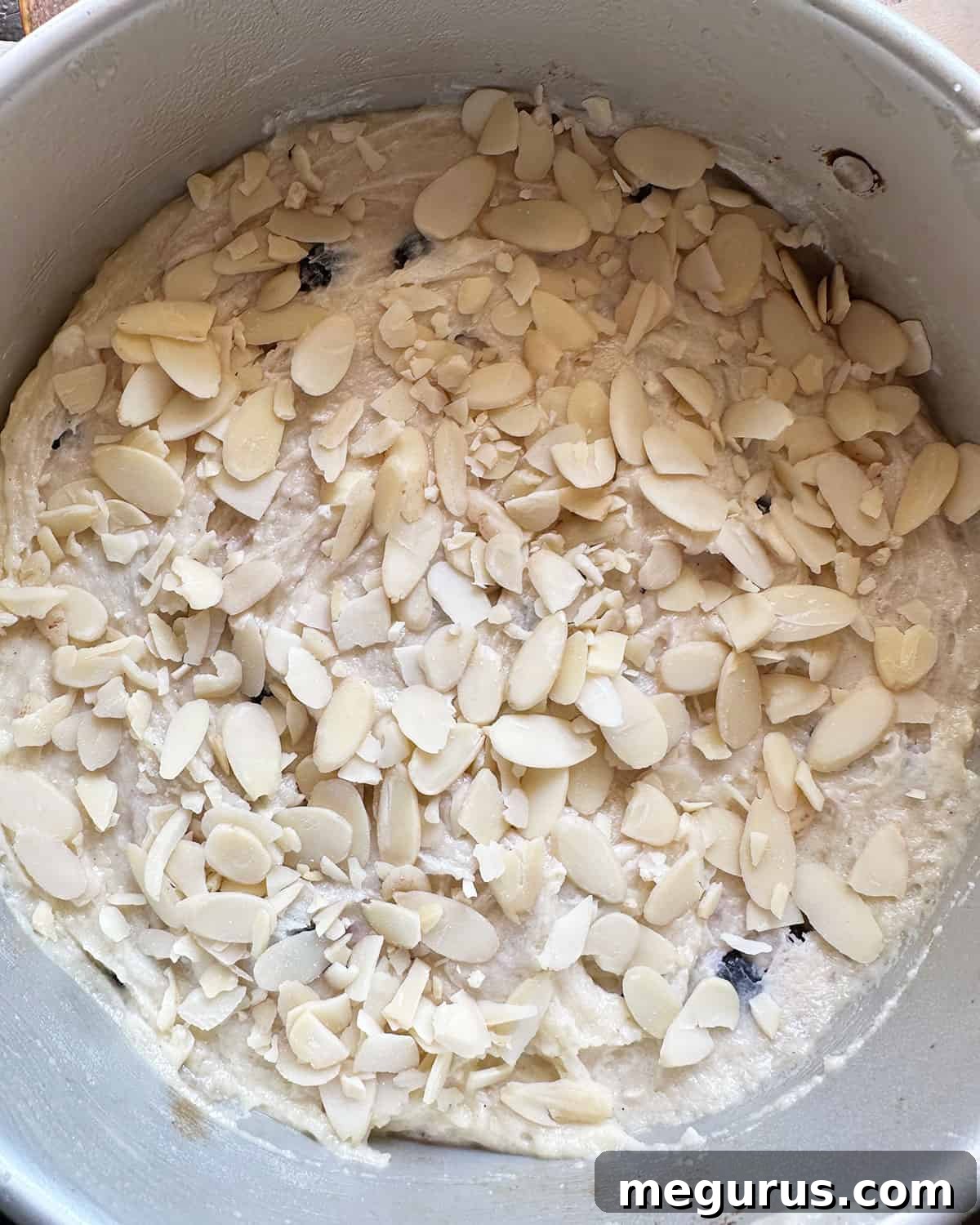 batter in pan with almonds scattered on top