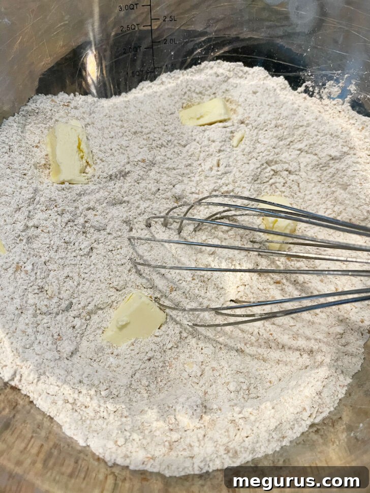Adding cold butter to the dry ingredients, preparing to rub it in.