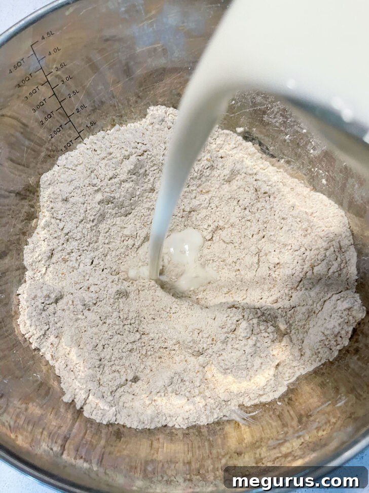Adding the buttermilk to the dry ingredients, initiating the dough formation.