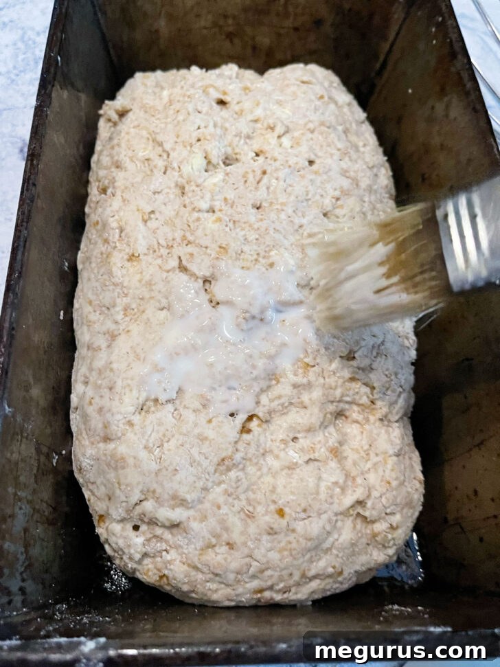 Brushing the loaf with milk for a golden crust.