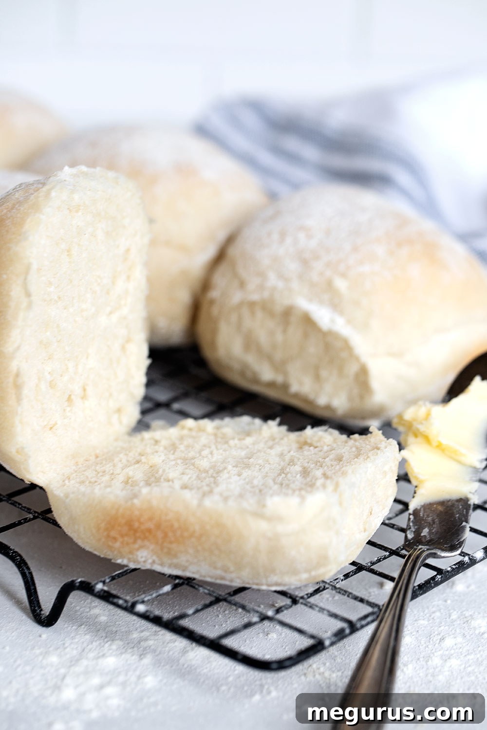 A freshly baked Irish blaa bun sliced open with a pat of butter, resting on a cooling rack.