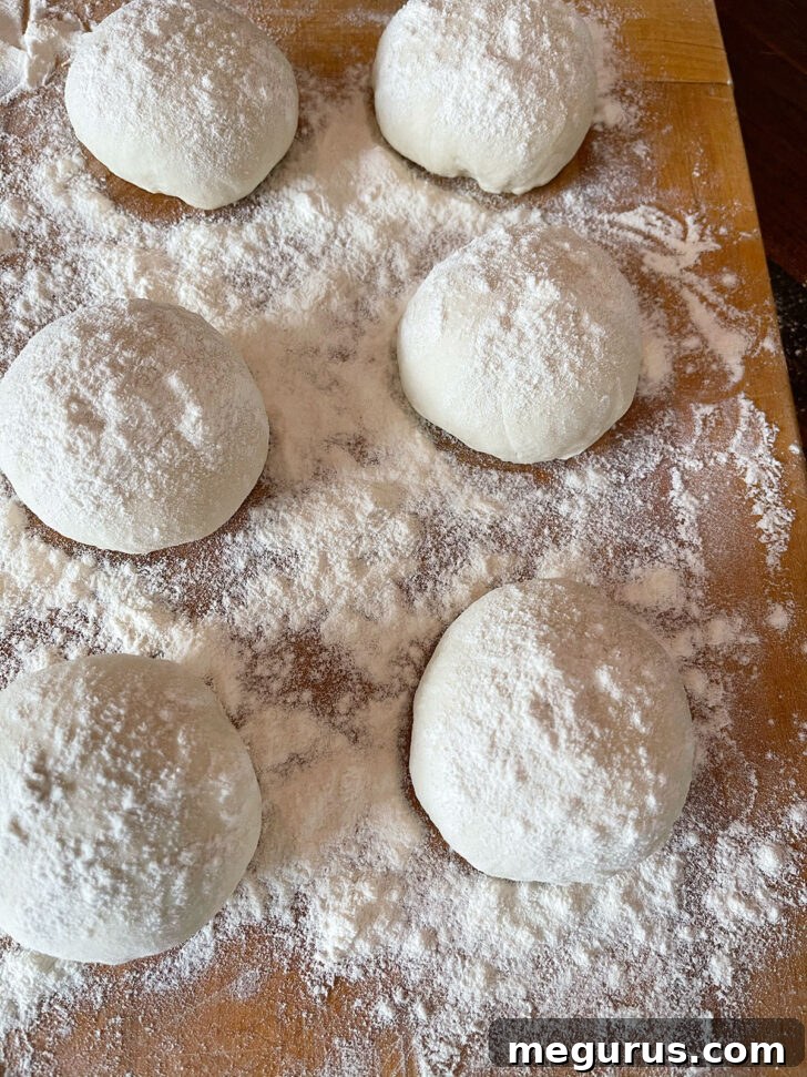 Generously flouring the shaped dough balls for their characteristic appearance.