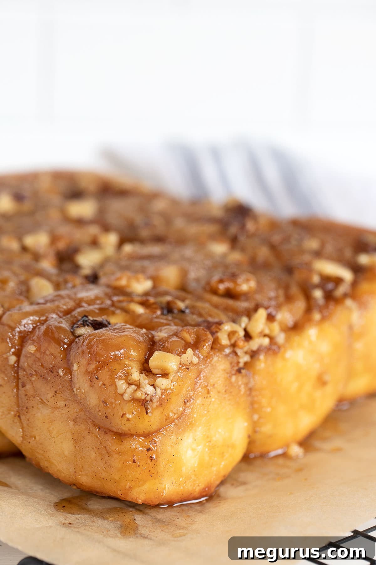 Close-up of golden brown maple walnut sticky buns, inverted and generously coated with sticky maple glaze and walnuts.