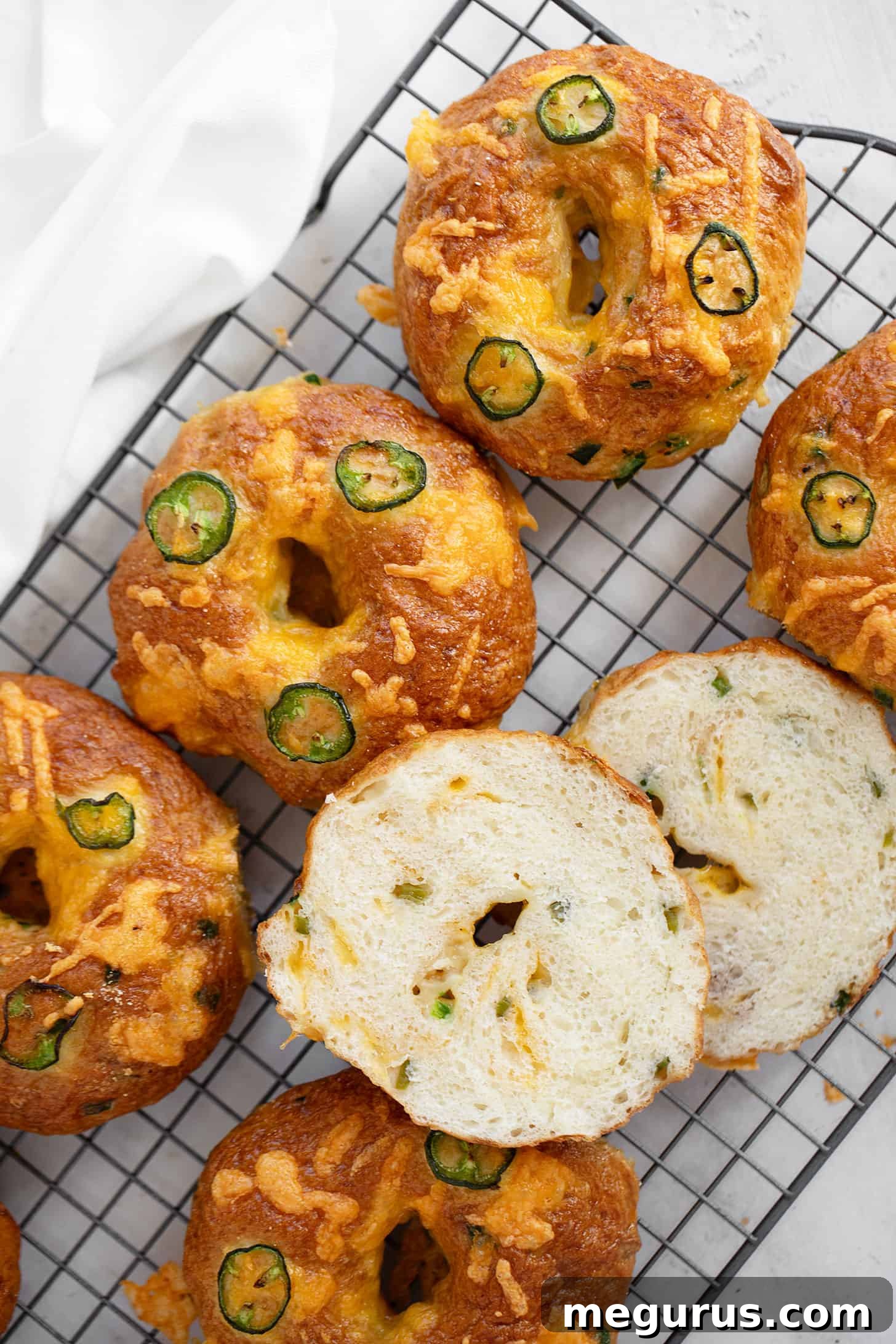 Close-up of baked jalapeño cheddar bagels on a cooling rack, highlighting their golden crust and melted cheese