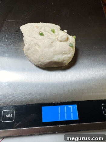 Individual dough pieces being weighed on a kitchen scale for consistent bagel size
